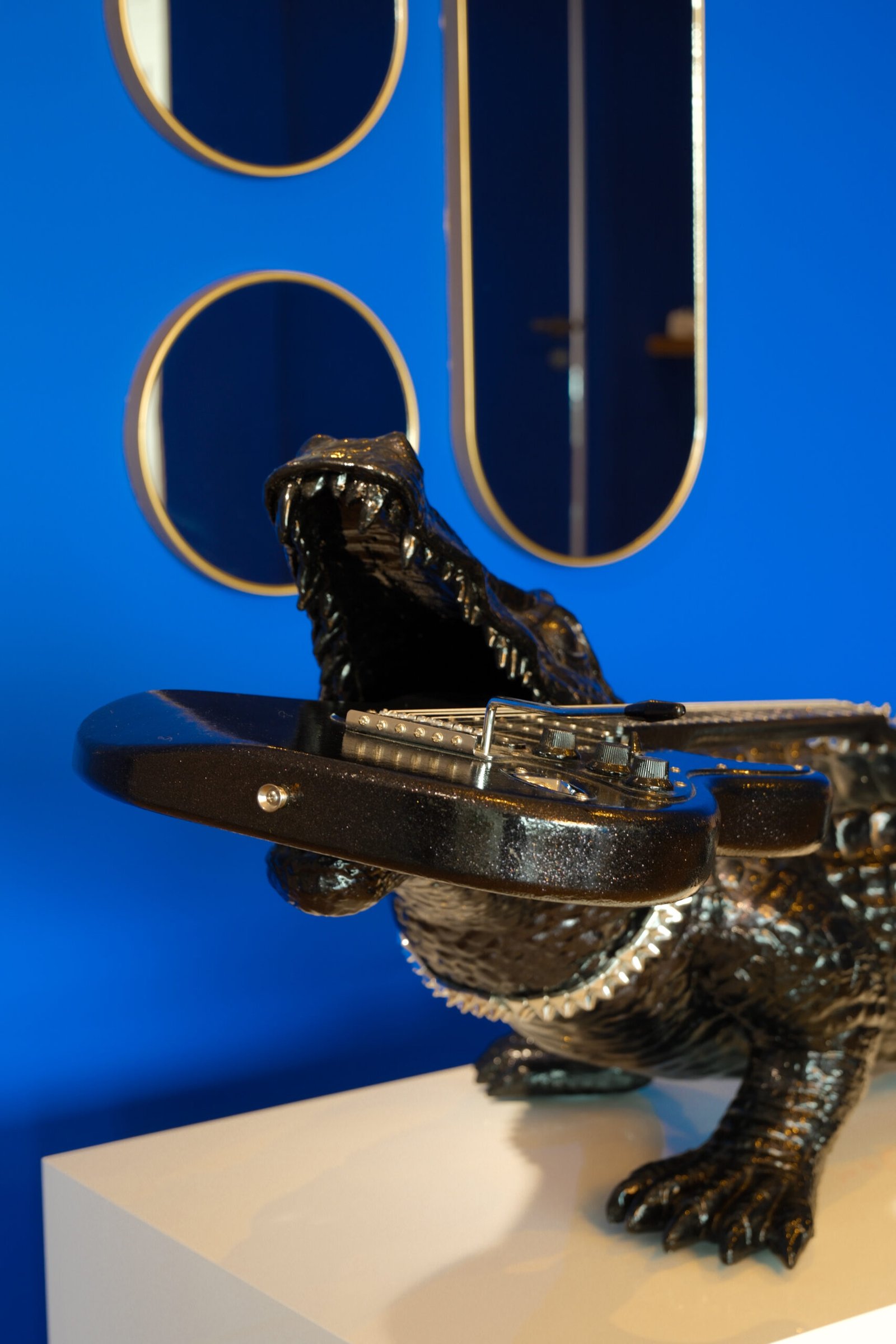 Sculpture de crocodile tenant une guitare électrique dans sa gueule